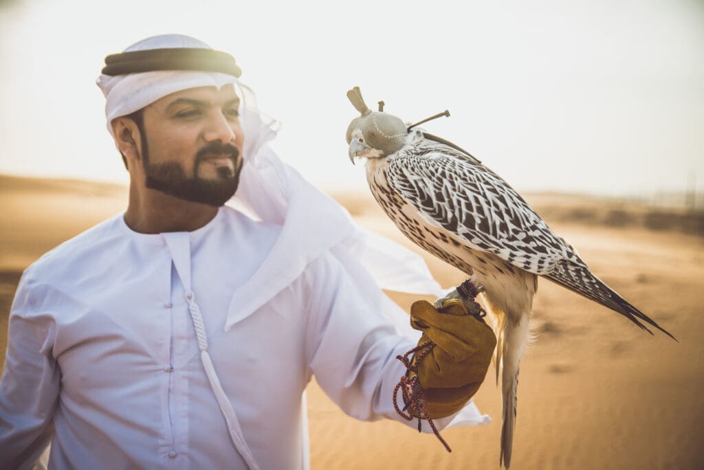 Arabic man with traditional emirates clothes walking in the dese