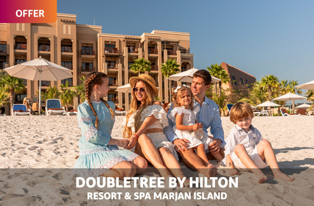 OFFER: DoubleTree by Hilton Resort & Spa Marjan Island - family of five sitting on the sand outside the resort